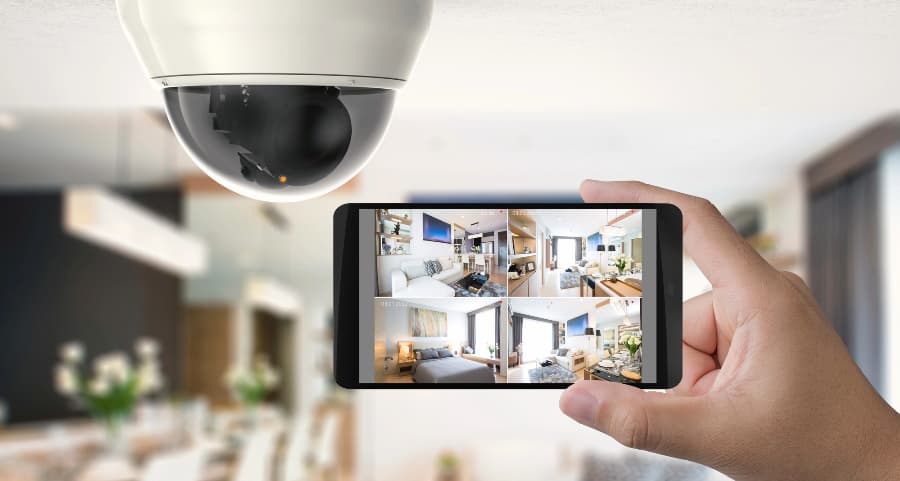 Homeowner holding smartphone with video feed from security cameras in Long Beach